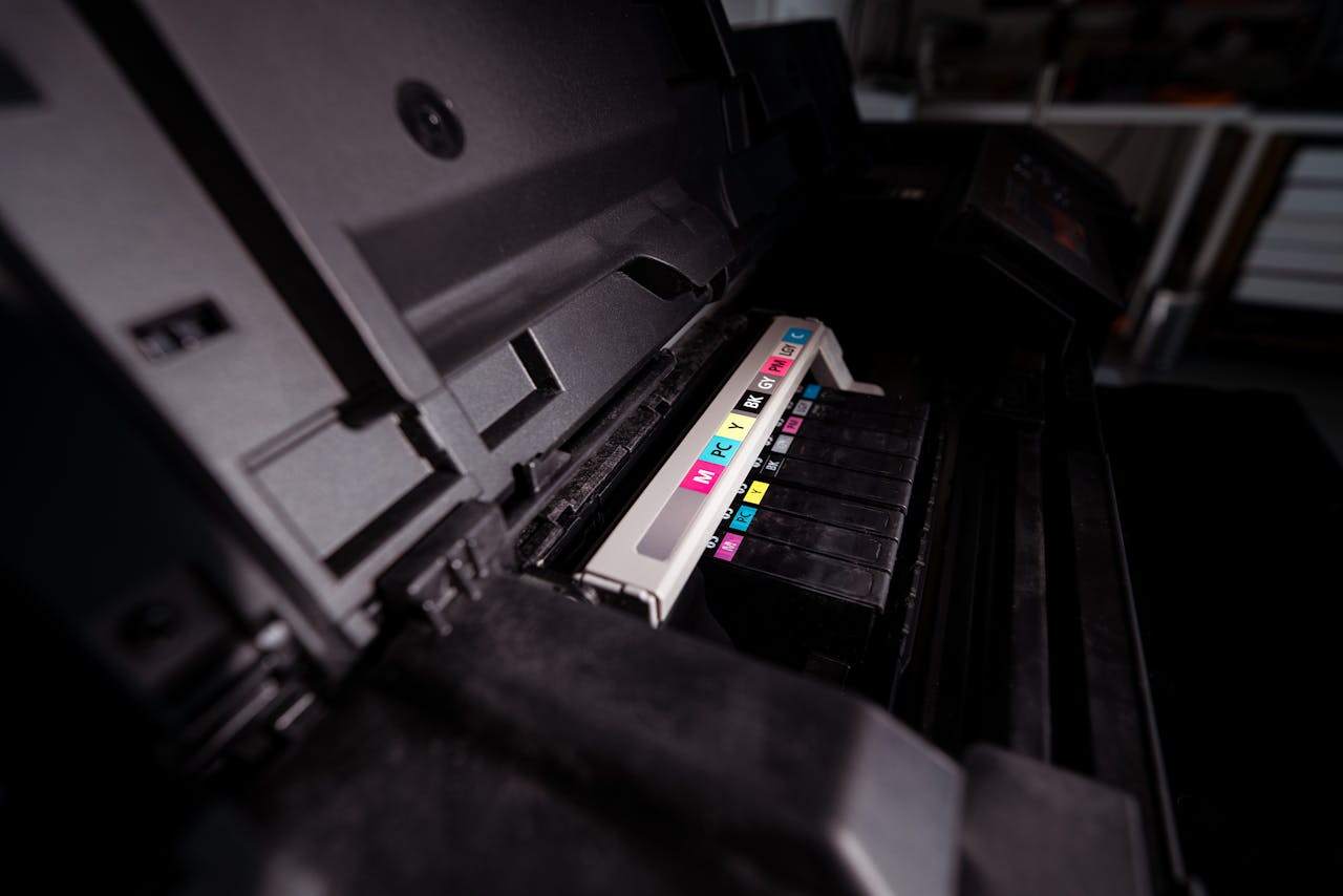 Crafting Captivating Headlines: Your awesome post title goes here Detailed view of open printer with visible CMYK ink cartridges in a dark setting.